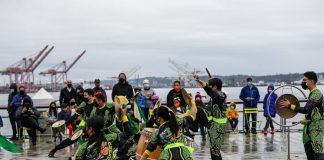 Dancers in green and black on a wet pier.