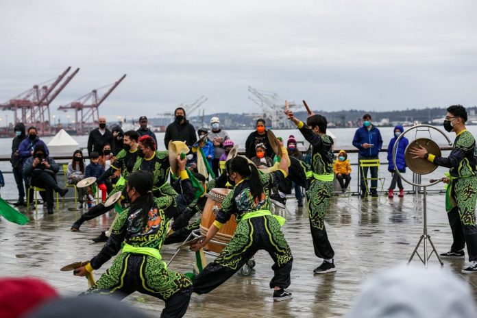 Dancers in green and black on a wet pier.
