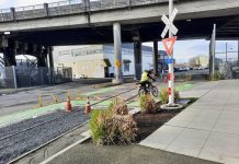 SDOT Adds Gravel Pit to Dangerous Burke-Gilman Track Crossing in Ballard A railroad crossing sign marks the spot next to some shrubs.