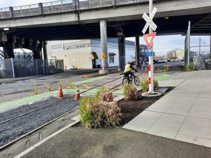 A railroad crossing sign marks the spot next to some shrubs.