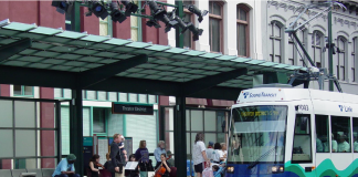 A light rail train approaches a station where a string quartet plays.