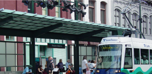 A light rail train approaches a station where a string quartet plays.