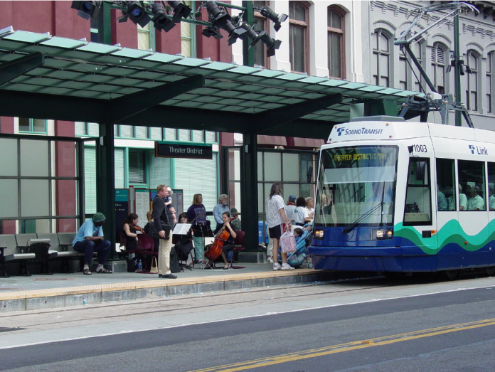 A light rail train approaches a station where a string quartet plays.