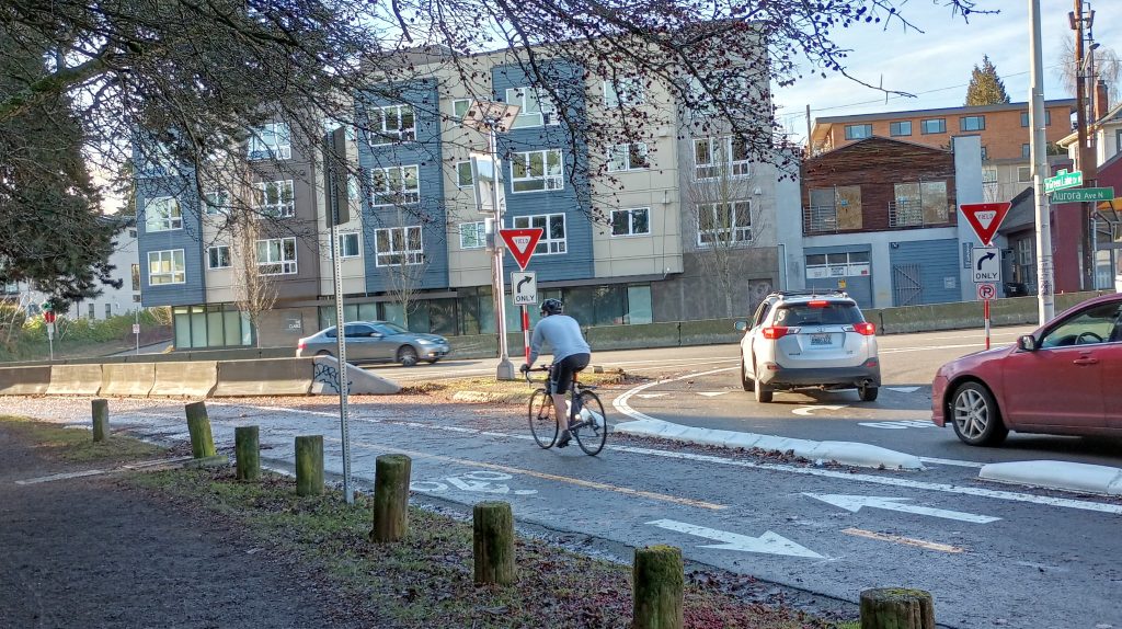 A cyclist heads toward the Aurora portion of the Green Lake Outer loop as drivers turn right onto the state highway