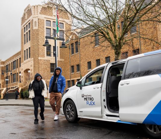 Metro Flex Launching In Early March, Replacing Other King County Microtransit Options White van with passenger door open waits for riders in front of a brick building.