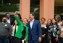 Mayor Harrell Unveils $970 Million Housing Levy Proposal Teresa Mosqueda reaches out her arm for a selfie with Mayor Bruce Harrell with several city staffers standing behind them.