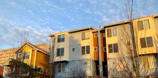Seattle Proposes Co-Living Ordinance Seeking to Meet New State Mandate Microhousing building next to a single family home. Blue sky overhead and sunset lighting.