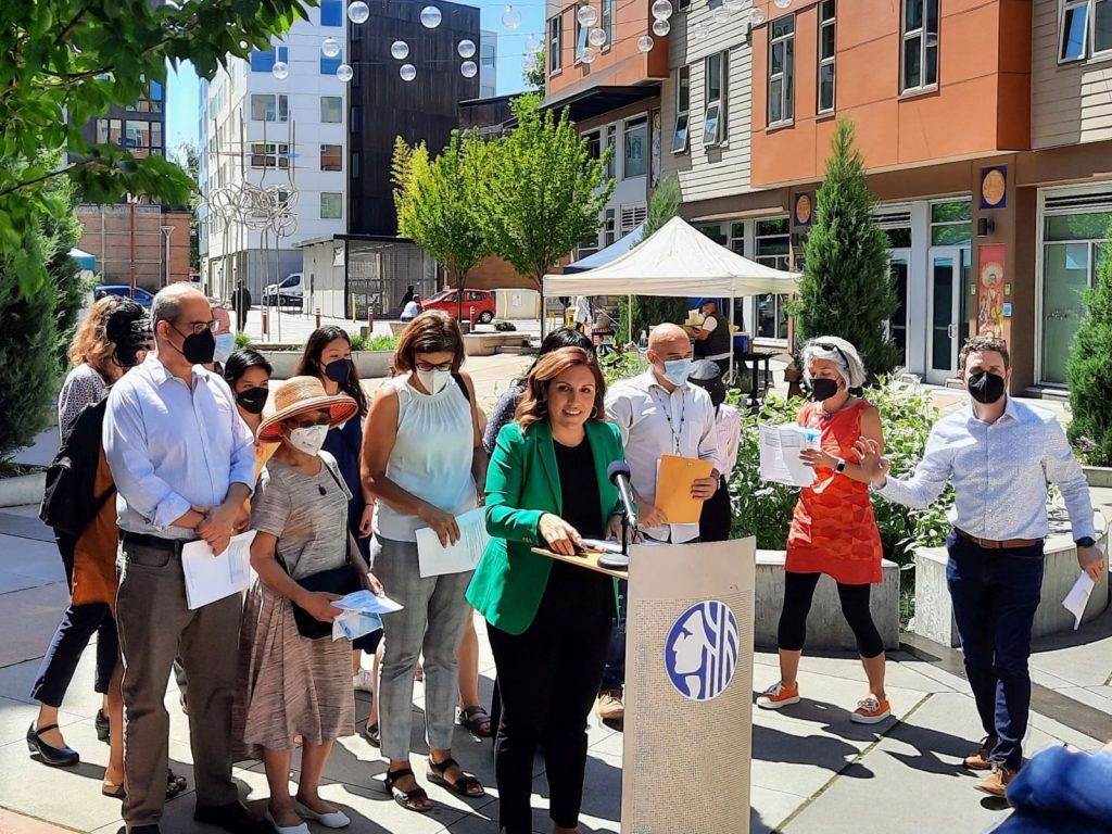 In this photo, Mosqueda announced 2022 affordable housing investments at Plaza Roberto Maestas alongside nonprofit leaders and Rep. Nicole Macri (D-43). The plaza includes trees and shrubs and is flanked by mid-rise apartments