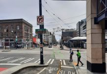 Sound Transit is Not Ready for Its Big Chinatown Station Decision Jackson Street with two pedestrians crossing at 5th Avenue next to the protected bike lane. The Chinatown station is in the background.