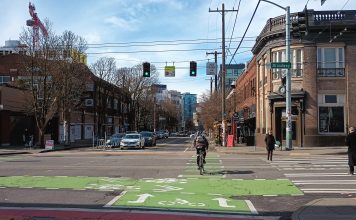 Legislature Abandons Most Traffic Safety Bills As Fatalities Continue To Mount Someone on a bike crosses the street as pedestrians walk in a crosswalk and drivers wait to turn at Broadway and Pike in Seattle