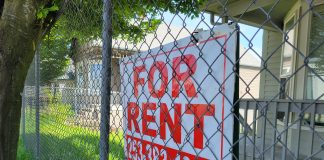 Chainlink fence with a for rent sign for a house.