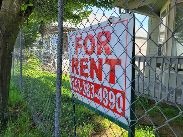 Chainlink fence with a for rent sign for a house.
