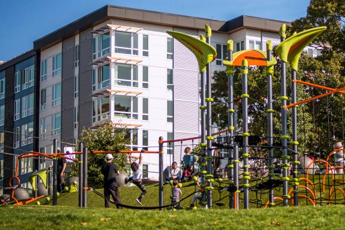 play equipment with children and an apartment building in the background