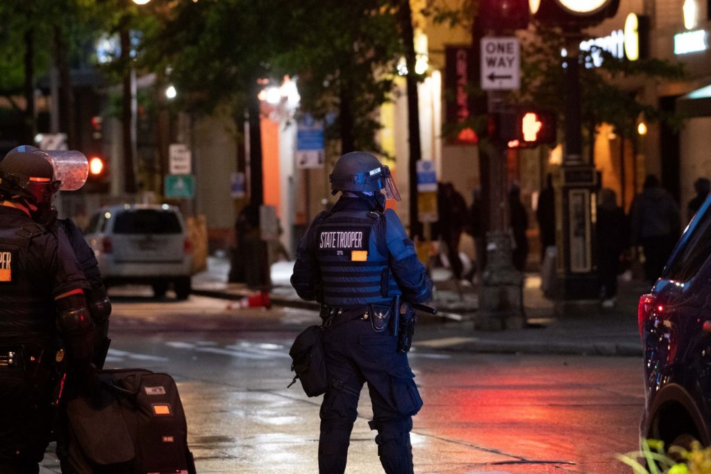 Covered in gear, a state trooper standing in an empty Seattle street at night.