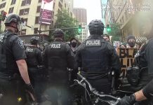 SPD Kettled Protesters in 2020, Escalated Violence, and Promoted the Commander A line of police offers in riot gear face off against protesters sporting Black Lives Matter signs along a Downtown Seattle street.