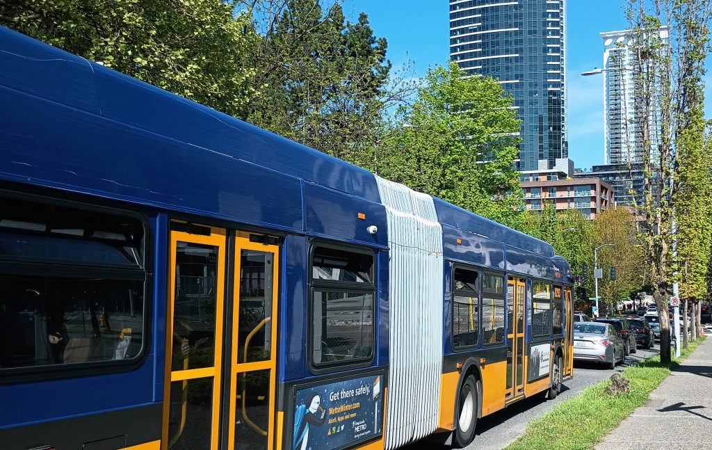 A double articulated bus sits in traffic on Denny Way