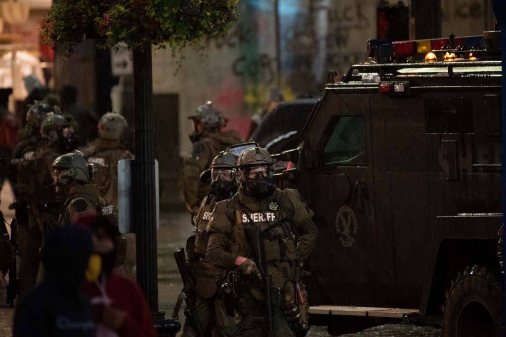 In riot gear, deputies stand by an armored vehicle on the first night of George Floyd protests in Seattle.