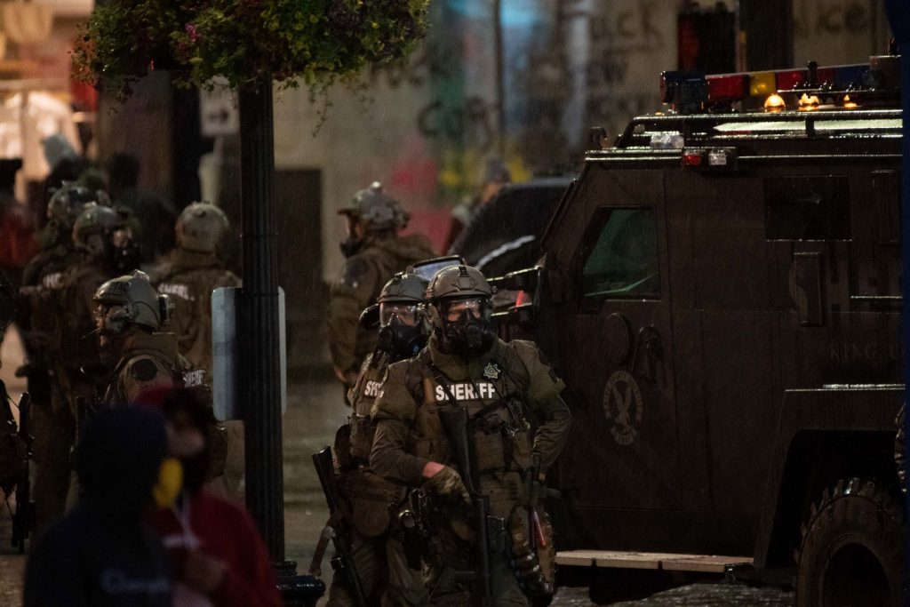 In riot gear, deputies stand by an armored vehicle on the first night of George Floyd protests in Seattle.