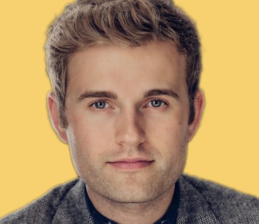 Ry Armstrong’s D3 Seattle Council Bid Stresses Shelter, Safety, and Sustainability Armstrong in a blazer. Yellow background behind.