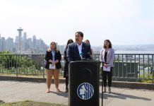 Seattle Releases Plan to Curb Climate Pollution from Buildings Bruce Harrell in a suit standing at a lectern. MLK Labor’s Executive Secretary-Treasurer Katie Garrow is to the left and OSE Director Jessyn Farrell to the right. A hazy Seattle skyline is in the background from Queen Anne vantage.