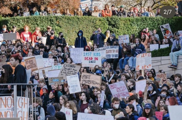 Students hold signs urging gun prevention and holistic approached to end violence.