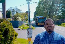 Transportation Wonk Joe Vinson Steps Up for SeaTac Council Joe Vinson stands on Military Road next to a crosswalk signal with a Route 156 bus in the background.