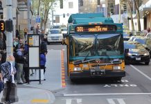 Metro Temporarily Suspending Six More Bus Routes This Month Ahead of September Cuts Route 301 using the 6th Avenue bus lanes in Downtown Seattle with a dozen riders waiting at a busy combined bus stop.