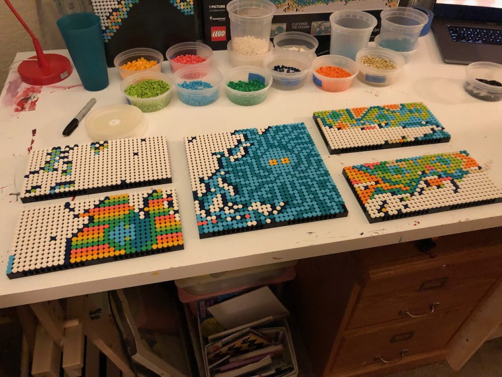 Unfinished Lego world map squares on a table with varied colorful patterns through the oceans.