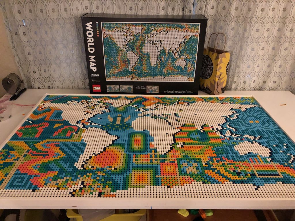 Finished Lego world map in front of its box with varied colorful patterns through the rest of the oceans.
