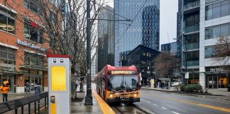 A RapidRIde C bus pulls up to the transit stop in front of Whole Foods at Denny Way intersection on a wet afternoon.
