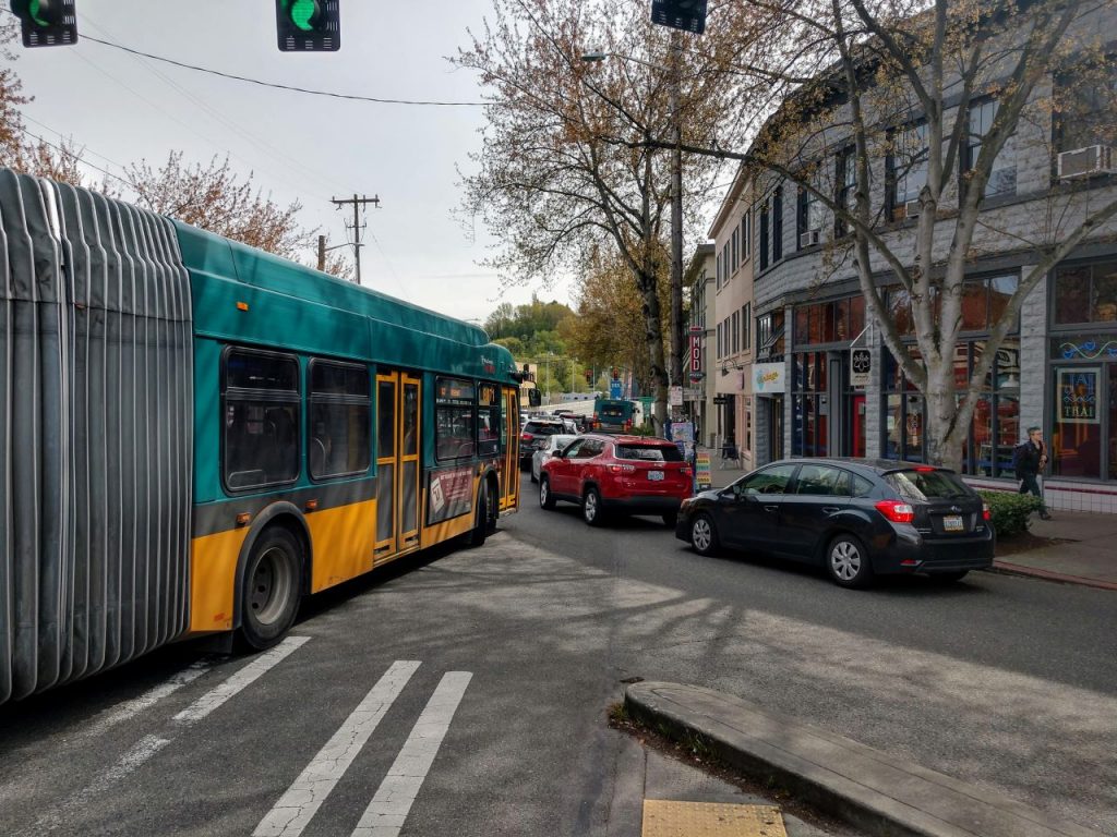 Several cars blocks the Route 62 bus stop on Fremont Avenue with the Fremont Bridge in the distance.