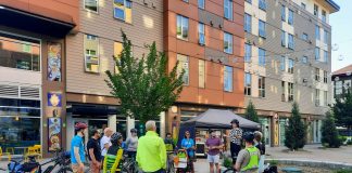 A dozen people gather in the courtyard plaza between the buildings that compose El Centro de La Raza complex.