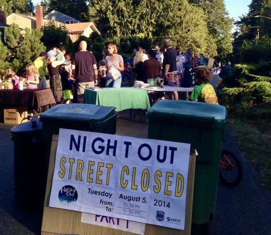 National Night Out Brings Neighbors (Briefly) Out on the Street A sign reads Night Out street closed with people gathered behind it socializing.