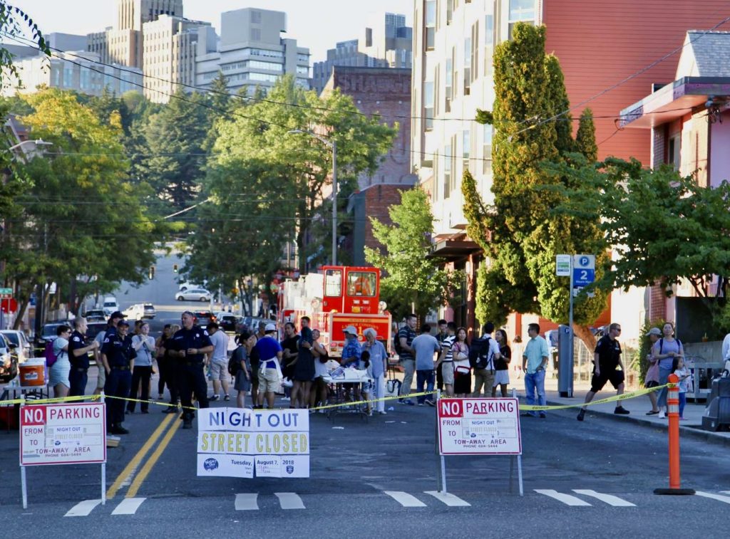 A street closed to traffic with the sign night out. People are gathered near a fire truck.