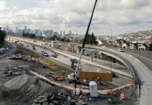 WSDOT Delays Promised I-5 to SR 520 Transit Ramp to 2030 Eastlake and the Seattle skyline is in the background as a construction crew adds a ramp at the SR 520 and I-5 interchange.