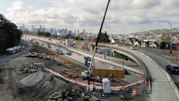 Eastlake and the Seattle skyline is in the background as a construction crew adds a ramp at the SR 520 and I-5 interchange.