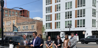 Spokane Council Member Zack Zappone and others in front of a new Spokane apartment building.