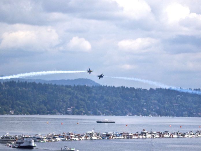 2011 Blue Angels Eric Frommer Two Navy Blue Angels planes pass each other over boats tied to a log boom in Lake Washington.