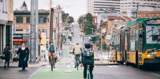 People ride bikes along Broadway. The bustling business district in Capitol Hill blends bike lanes, pedestrian spaces, bus service, streetcar tracks, and vehicle traffic.