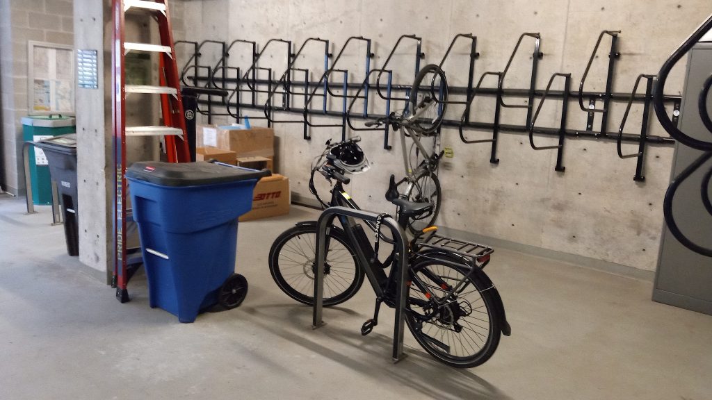 A basement room with many bike racks and some recycling bins.