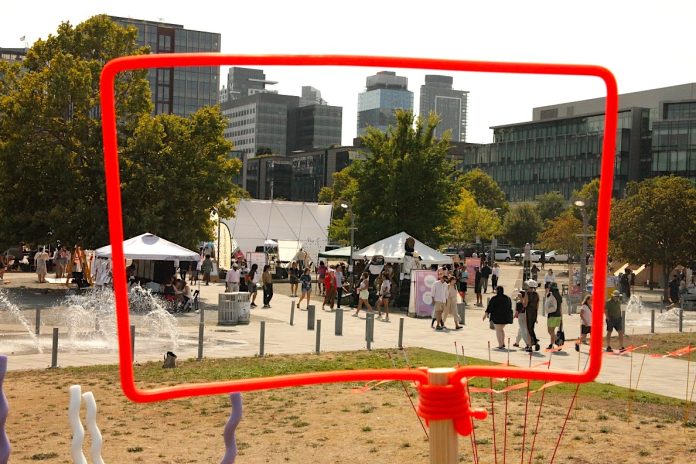 Looking through a discussion bubble frame at the Block Party activities with the skyline behind.