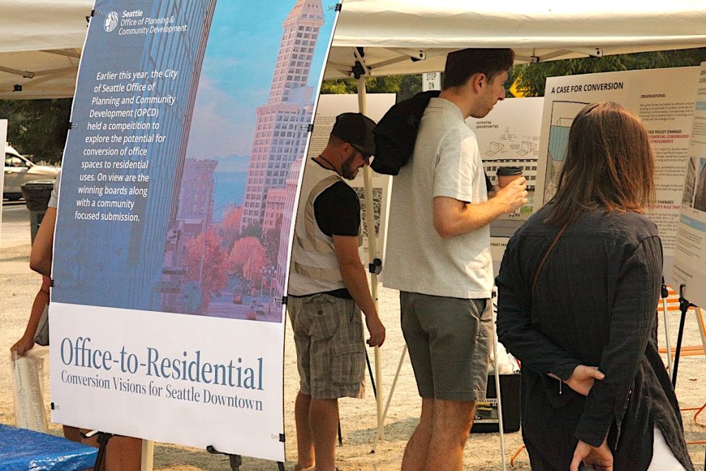 People standing in front of case study posters about office conversions to residential spaces.