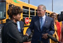 Seattle-Area Schools Slowly Electrify Bus Fleets  Governor Inslee shakes the hand of a Tacoma high school student standing in front of the state's first electric school bus in 2019.