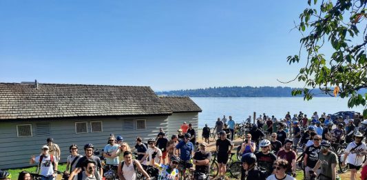 A crowd of more than 100 bicyclists assembled with Lake Washington in the background.