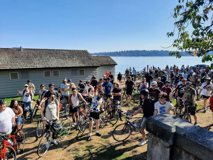 A crowd of more than 100 bicyclists assembled with Lake Washington in the background.