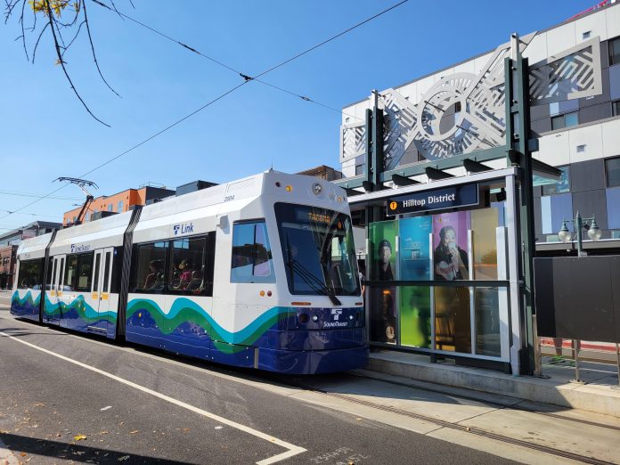 Colorful photos on glass and geometric art stand out as a streetcar arrives at the Hilltop District T-Line station.