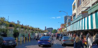 Cars parked and motoring past shops at Pike Place Market.