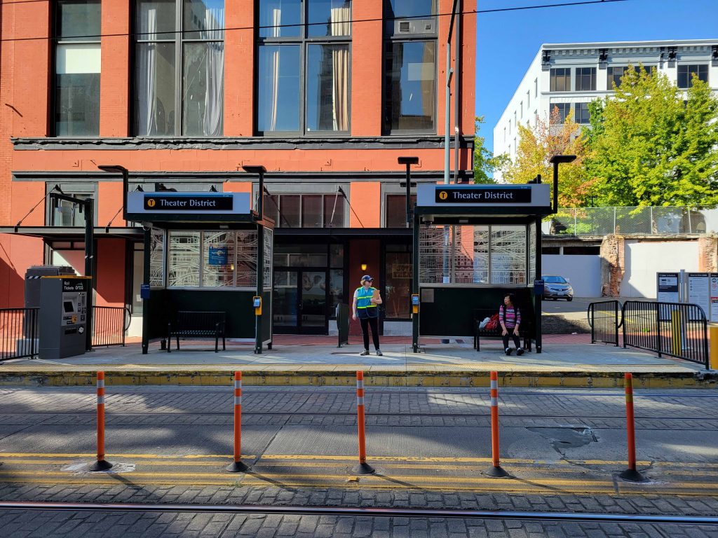 Tacoma T-Link station now called Theater District station in front of a red building.