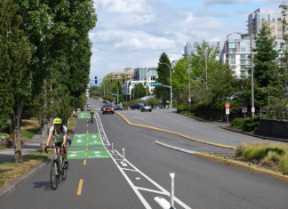 Bellevue Seeks Public Feedback on 15 Miles of New Bike Infrastructure Looking down NE 12th Street with a rendering of a cycletrack with painted lines, green painted boxes and flexible posts.