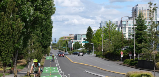 Looking down NE 12th Street with a rendering of a cycletrack with painted lines, green painted boxes and flexible posts.